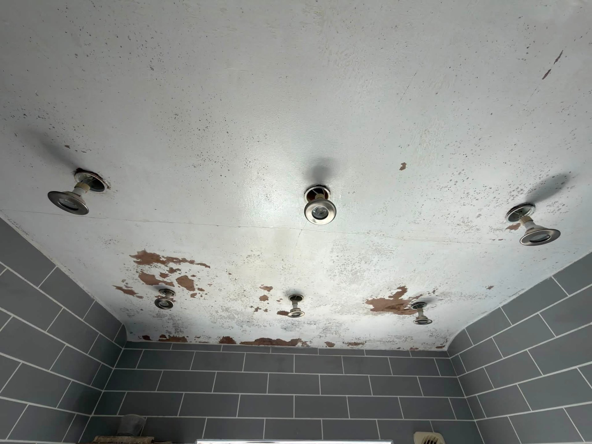 Bathroom ceiling before work, with flaking paint and moisture damage